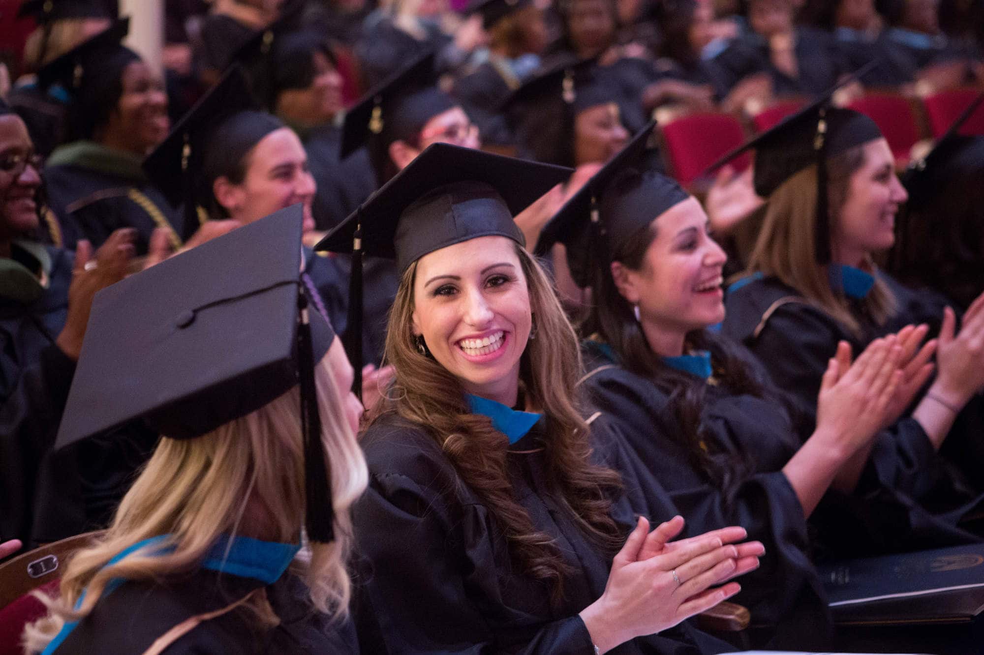 Occupational therapy graduates clap during a commencement ceremony