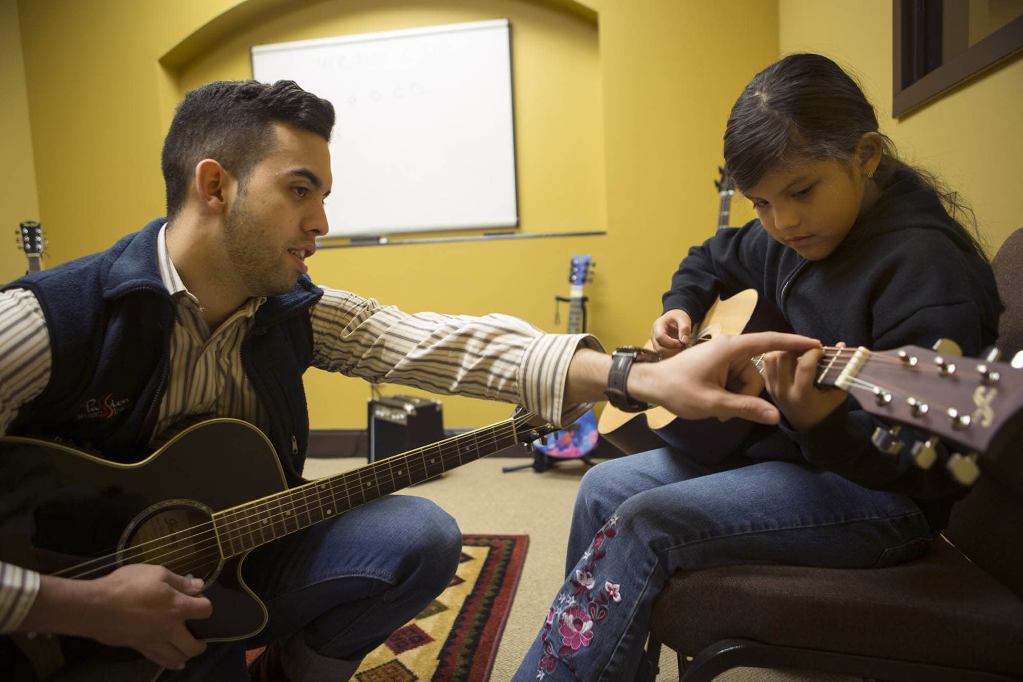 Gabriel Lopez teaches guitar to a young student
