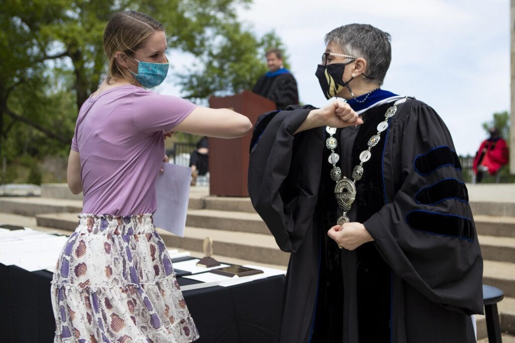 Dr. Skleder and student holding award touch elbows. 3