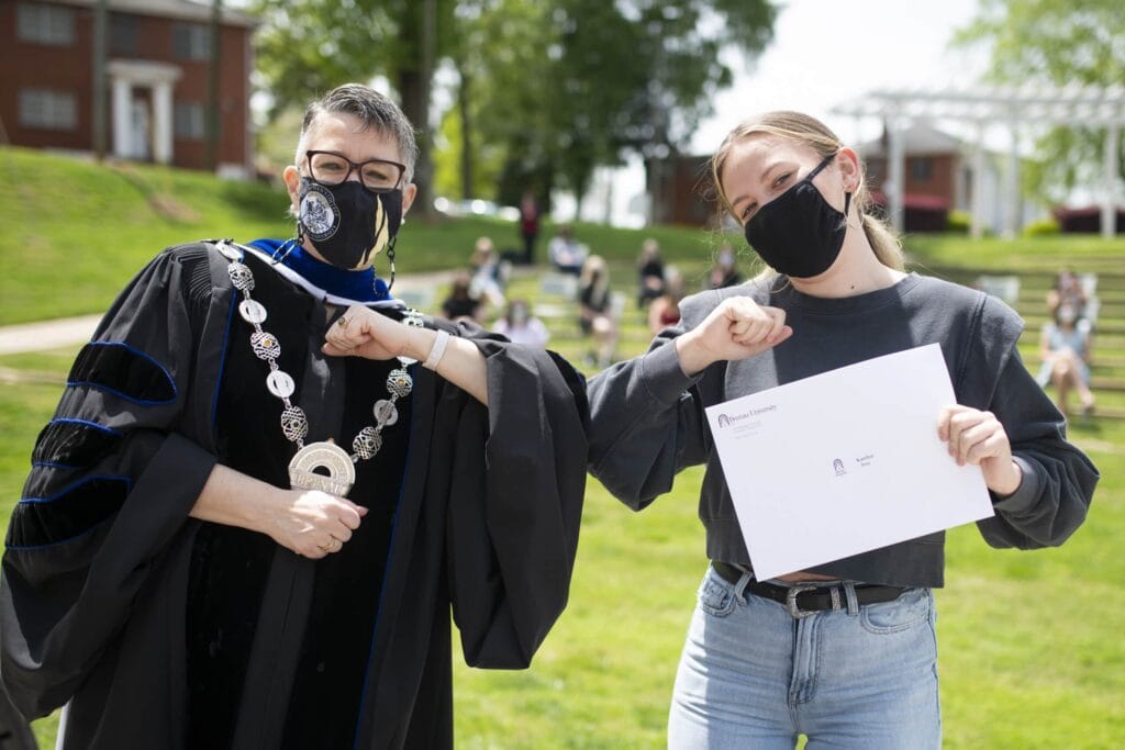 Dr. Skleder and student holding award touch elbows. 7