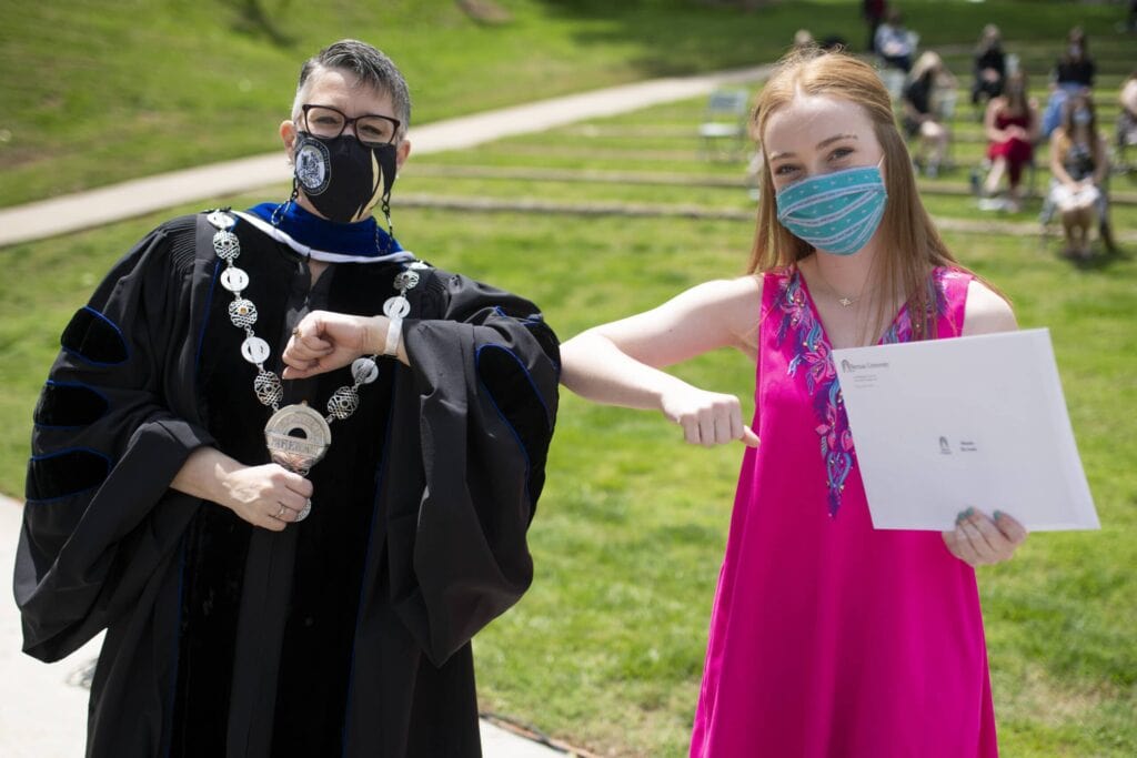 Dr. Skleder and student holding award touch elbows. 8