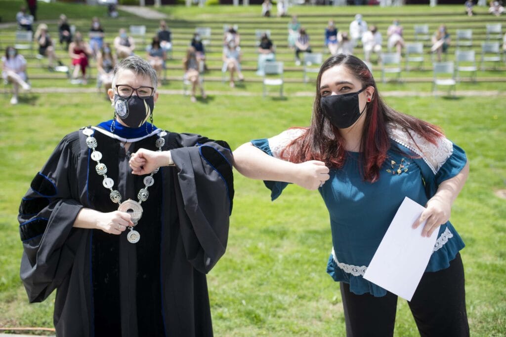 Dr. Skleder and student holding award touch elbows. 11