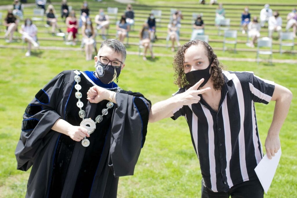 Dr. Skleder and student holding award touch elbows. 13