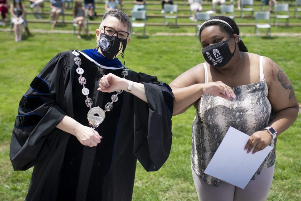 Dr. Skleder and student holding award touch elbows. 14