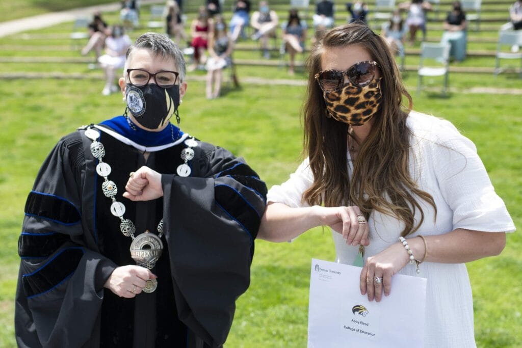 Dr. Skleder and student holding award touch elbows. 21