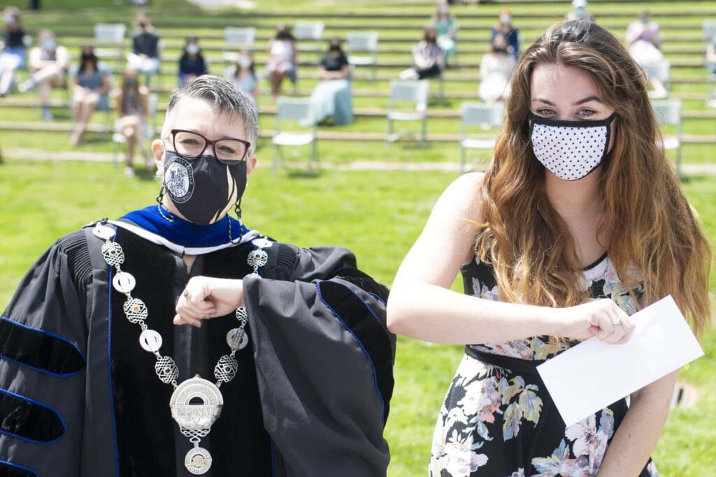 Dr. Skleder and student holding award touch elbows. 22