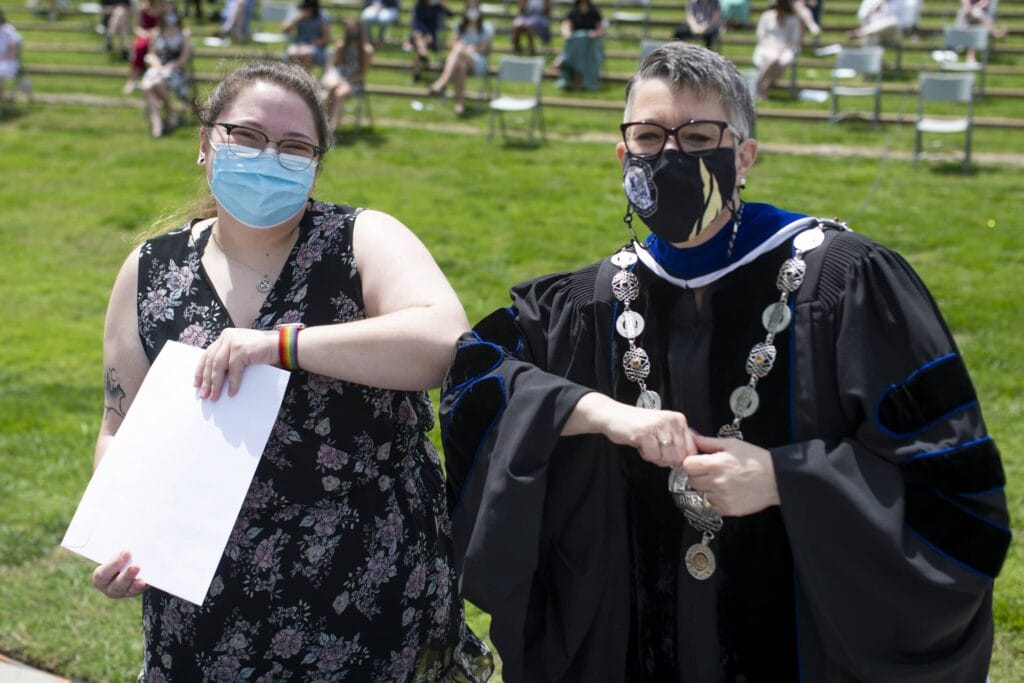 Dr. Skleder and student holding award touch elbows. 26