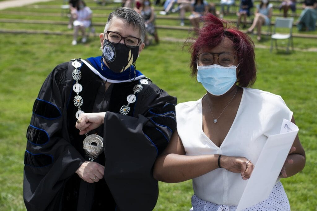Dr. Skleder and student holding award touch elbows. 27