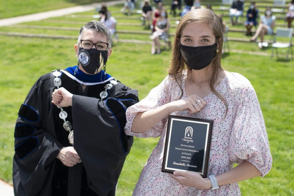 Dr. Skleder and student holding award touch elbows. 28