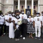 The family of Keiara Ivory Lyons in matching shirts and masks holding her diploma cover.