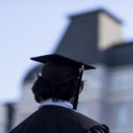 back of person in regalia and grad cap against Pearce Auditorium