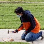 A student smashes a plate with a hammer.