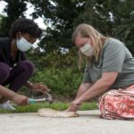 A student and professor work on smashing a plate.