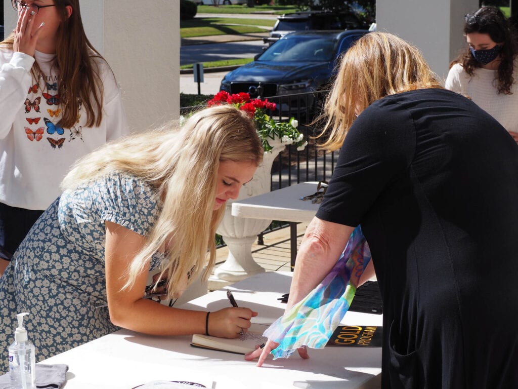 student signs book outside