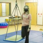 A student stands with occupational therapy equipment.