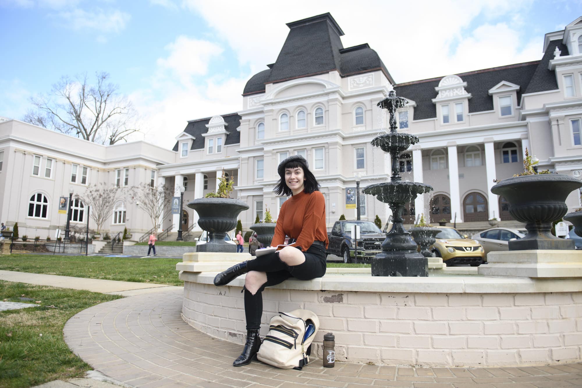 A student studies on the fountain on front campus