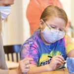 A Brownie Girl Scout paints a bowl