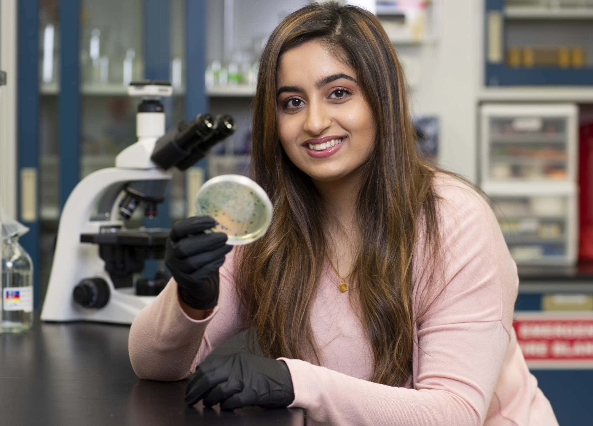 A first generation student poses for a photo inside a lab