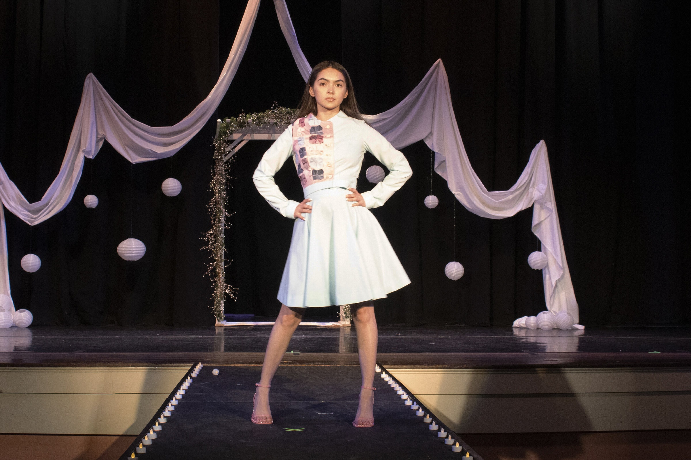 Student poses in student-made dress during fashion show