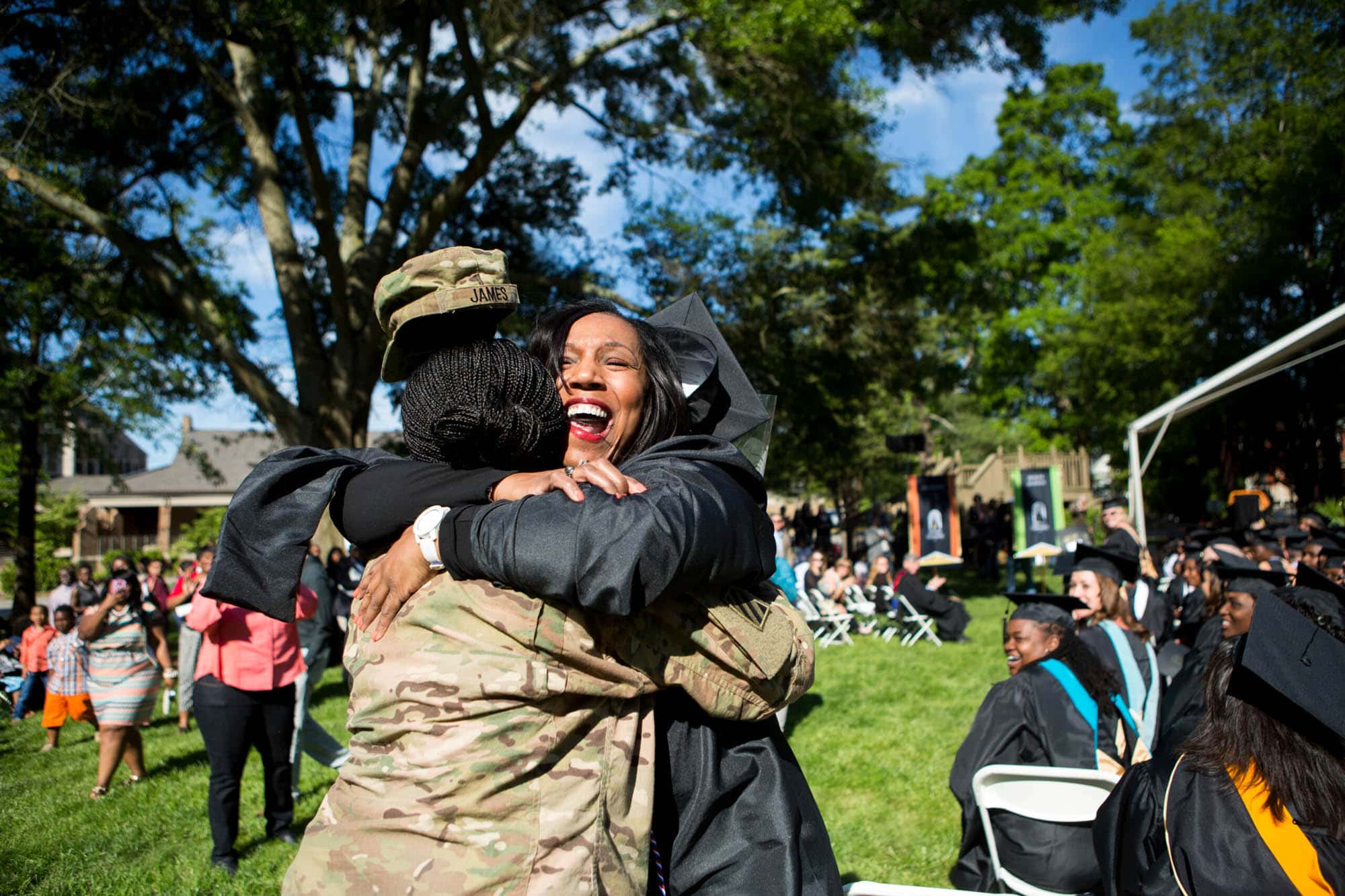 soldier in fatigues hugs mother in grad gown