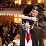 A graduate hugs President Anne Skleder after getting her diploma