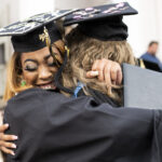 Two Women's College graduates hug after getting their diplomas