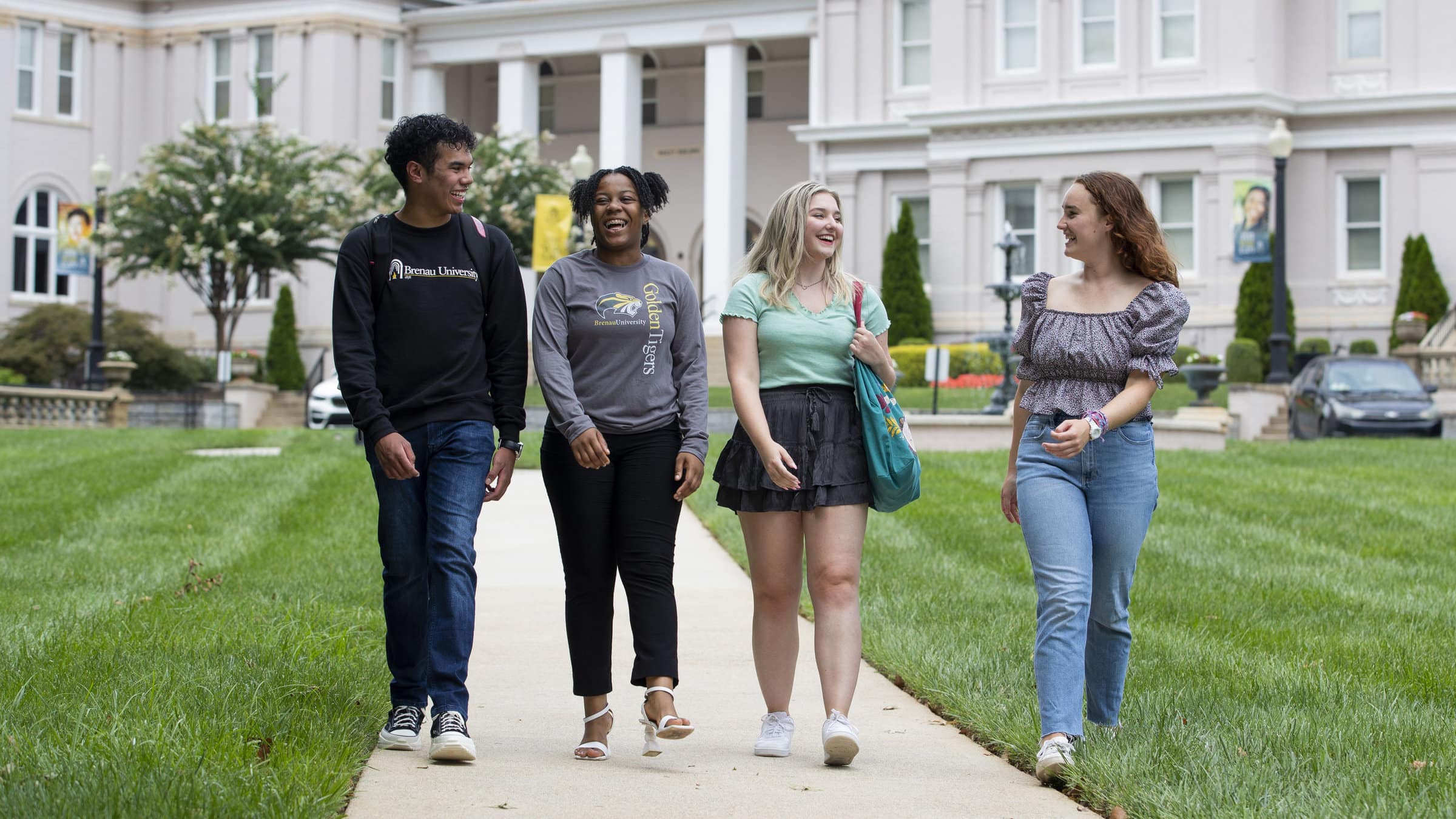 A group of four students walk on Brenau's front campus