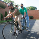 Two people, one blindfolded, try blind tandem biking.