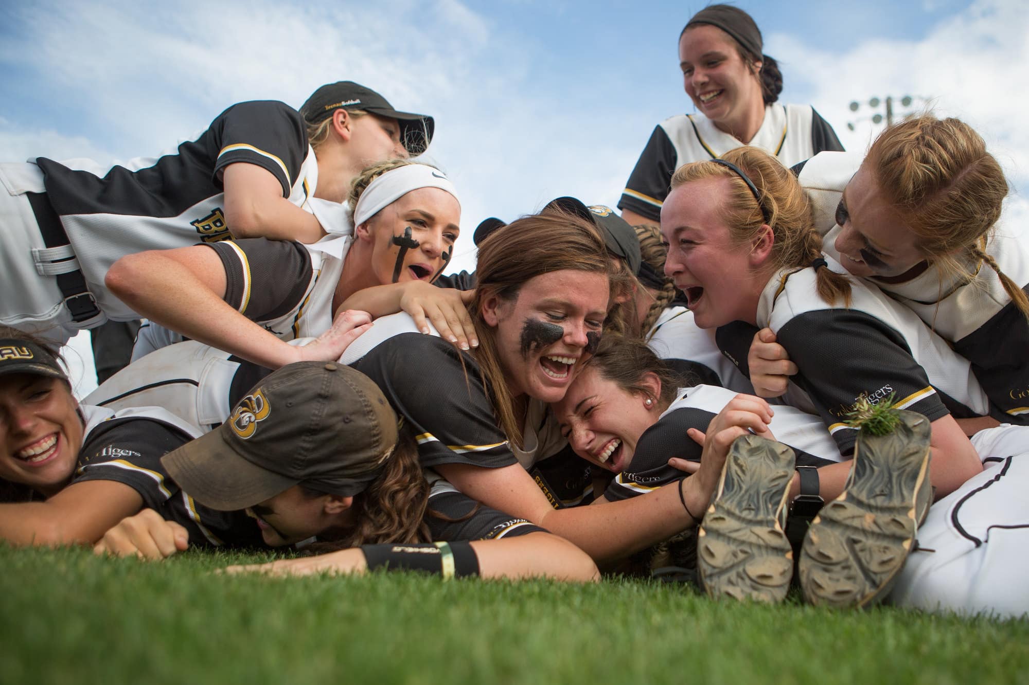 Softball players jump on each other after winning a conference championship