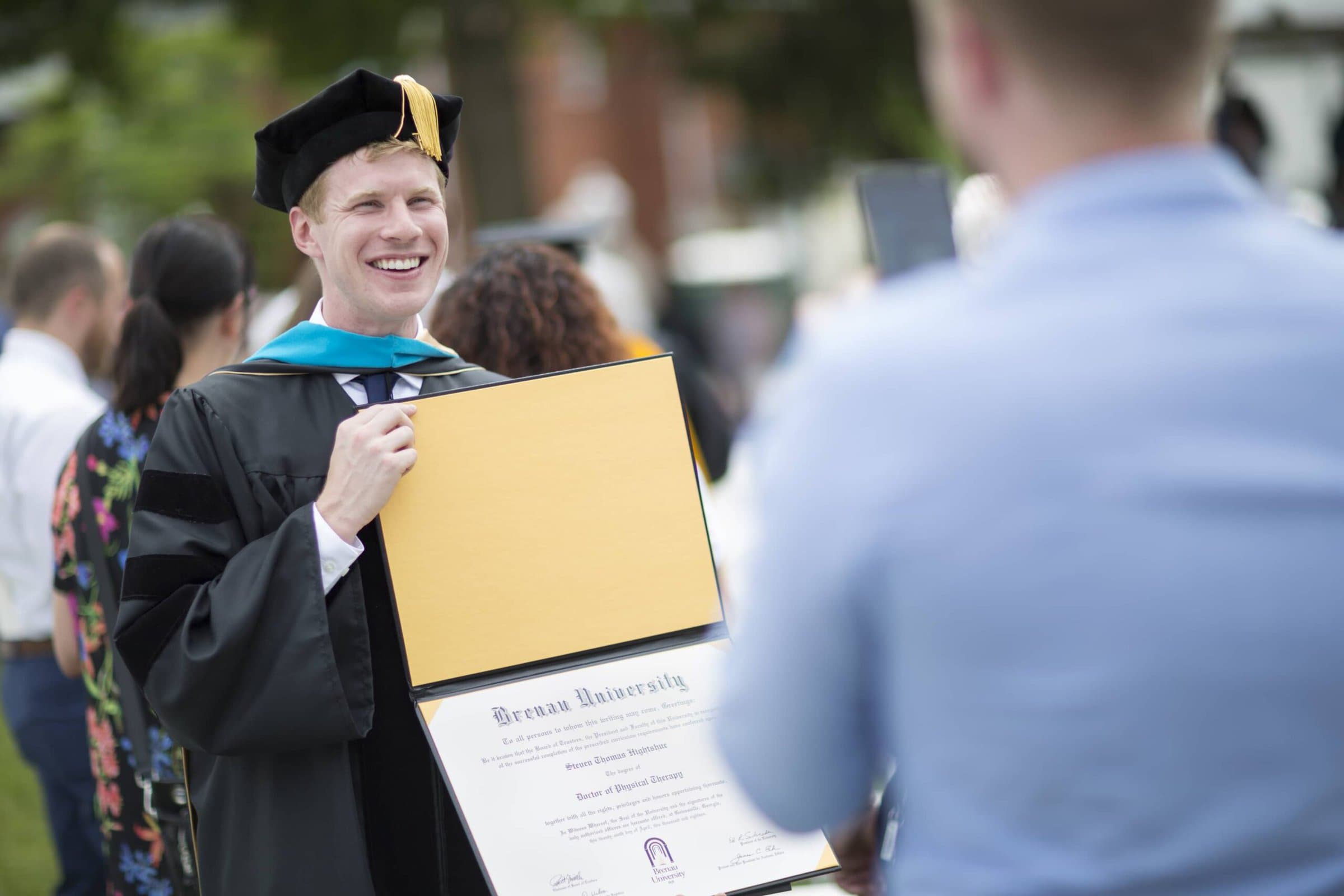 Steven Hightshue, DPT, shows off his diploma for his brother, John Hightshue, following the 2018 Spring Commencement Ceremony on Saturday, May 5, on Brenau University's historic Gainesville campus. (Nick Bowman for Brenau University)