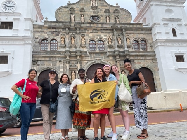 Brenau president, faculty and students with flag in front of colonial building in Panama