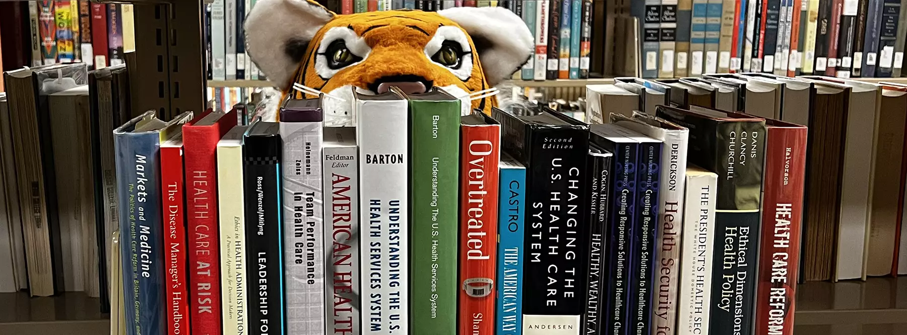 Mascot HJ peering over a shelf of books