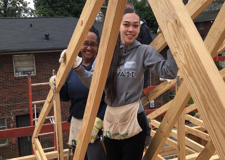 Two students standing in the frame of a house.