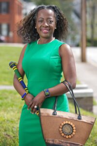 Margie Gill poses for a photo with an honorary warrior stick from Rwanda along with a purse and two bracelets gifted to her.