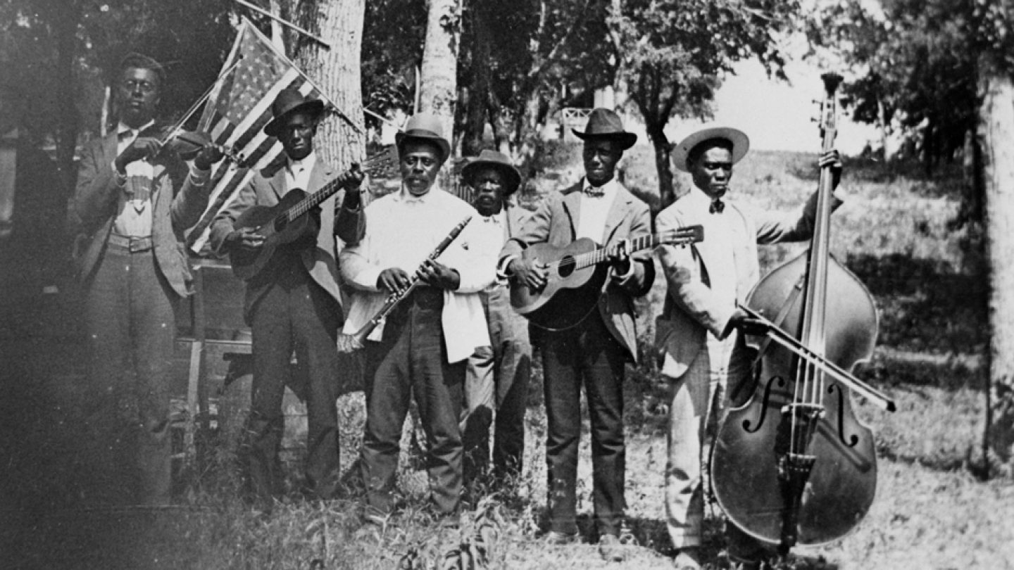 African-American men with instruments  stand outside in black and white photo. 
