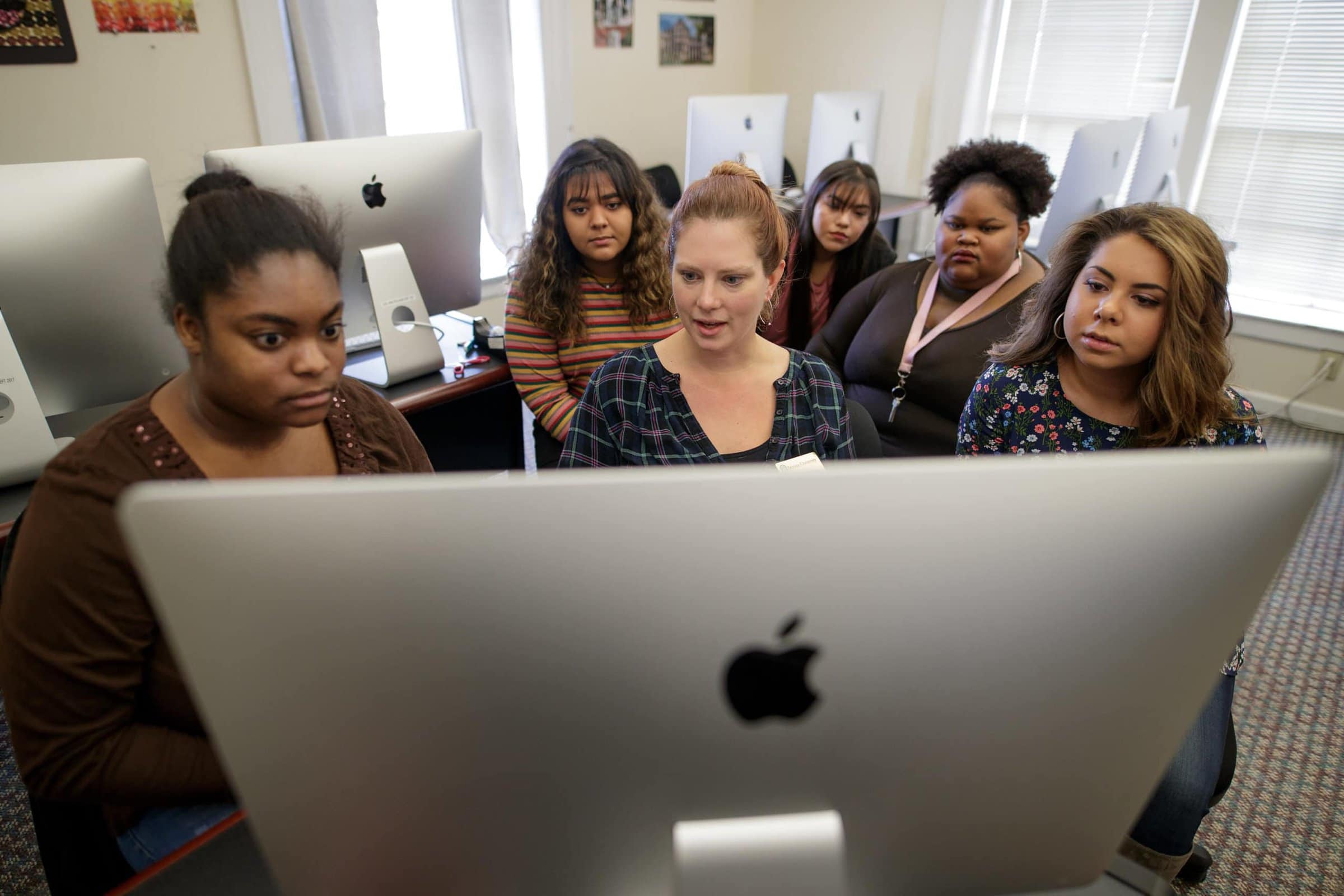 Students gather around Professor Wilburn at a Mac computer