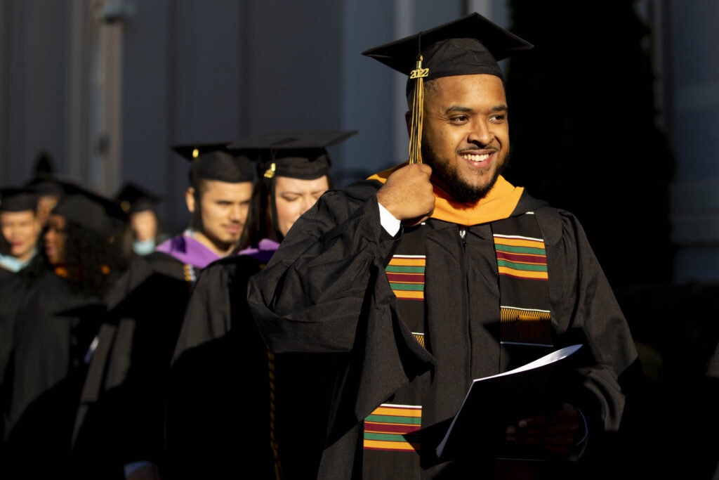 A graduate student waits in line to process into the auditorium.