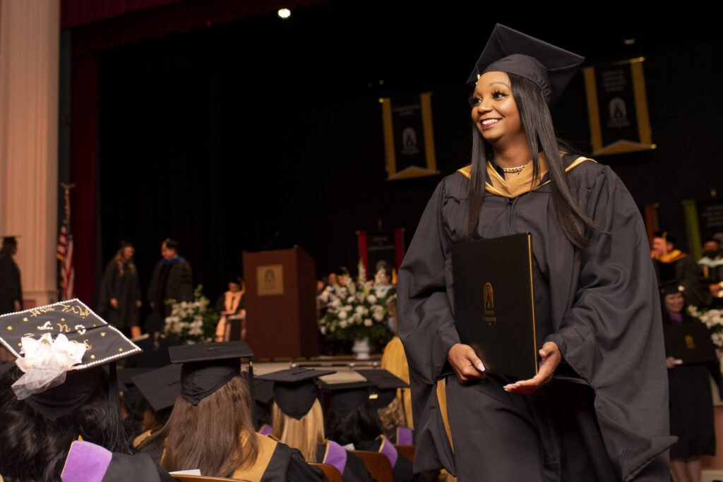 A graduate returns to her seat after receiving her diploma.