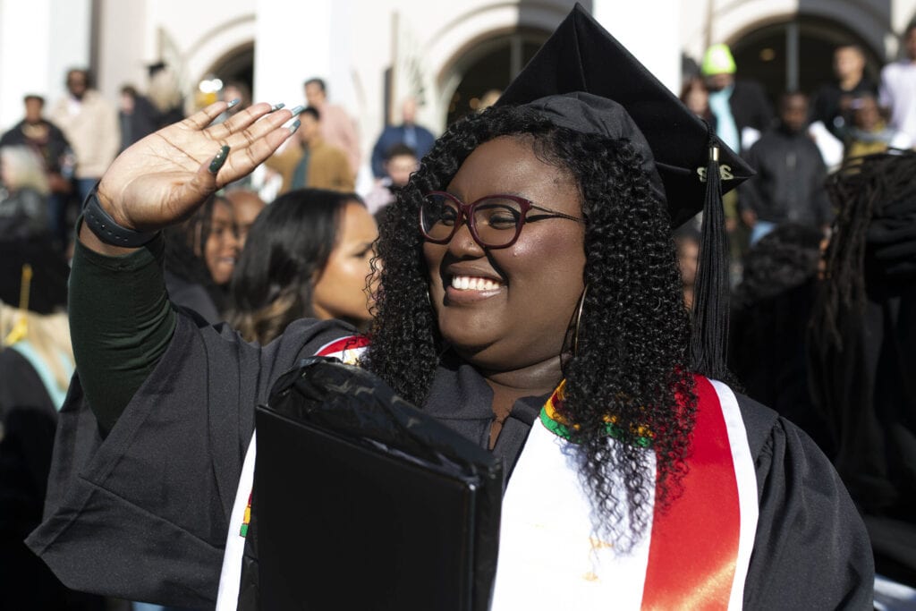 A graduate waves to her friends after the undergraduate commencement ceremony