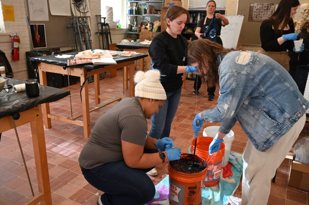 Three students dye fabric with indigo during International Week.