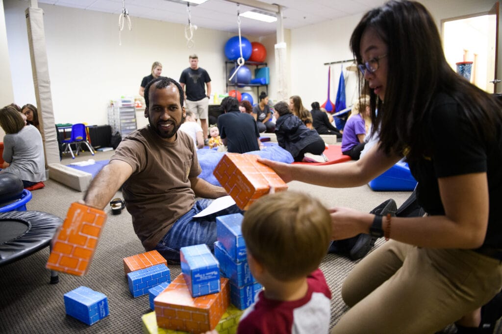 Occupational therapy students work with a toddler in a pediatric lab