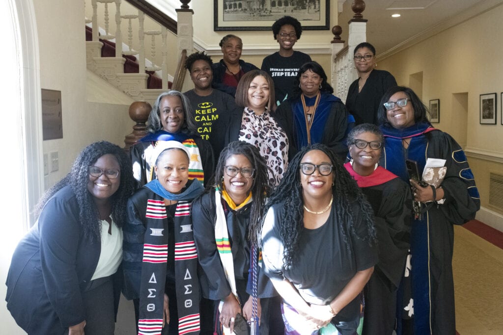 Group of students, faculty and staff pose on stairs.