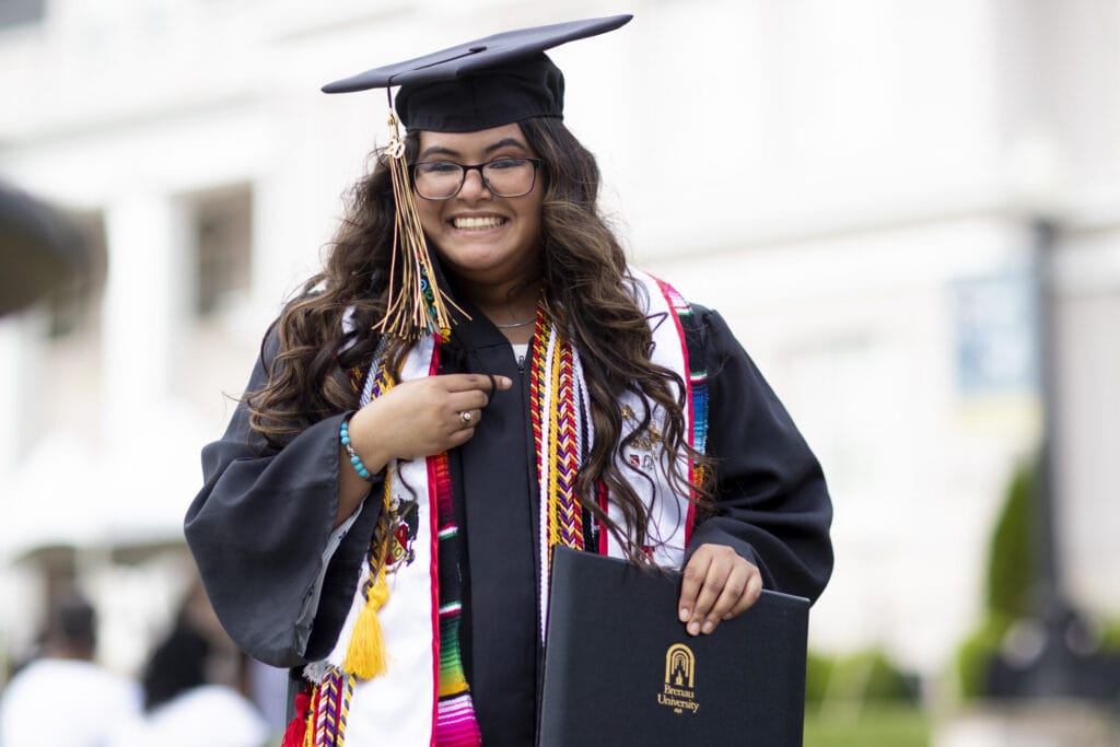 smiling graduate with multiple honor cords and stoles