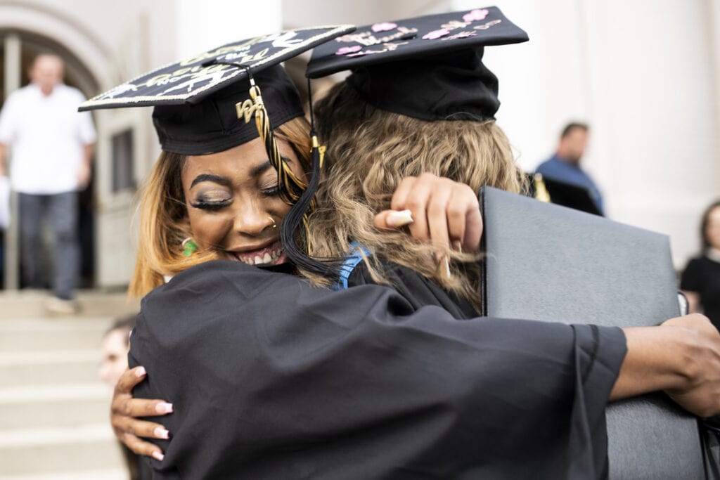 Two women in graduation robes embrace