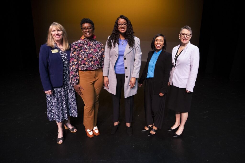 five women stand together on stage for Women's Leadership Colloquium