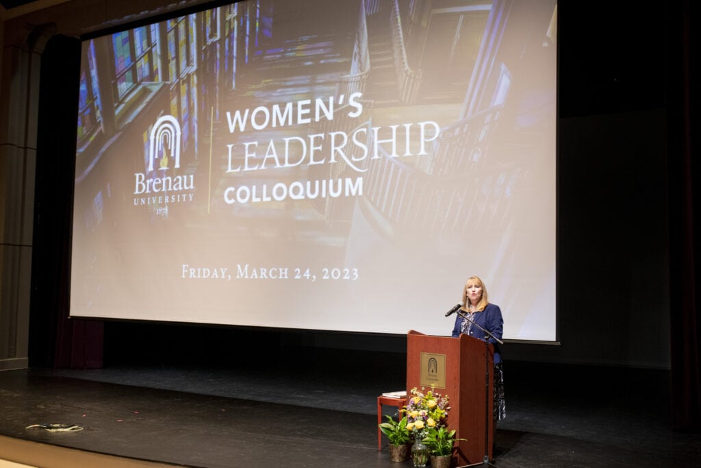 large screen depicts title for Women's Leadership Colloquium