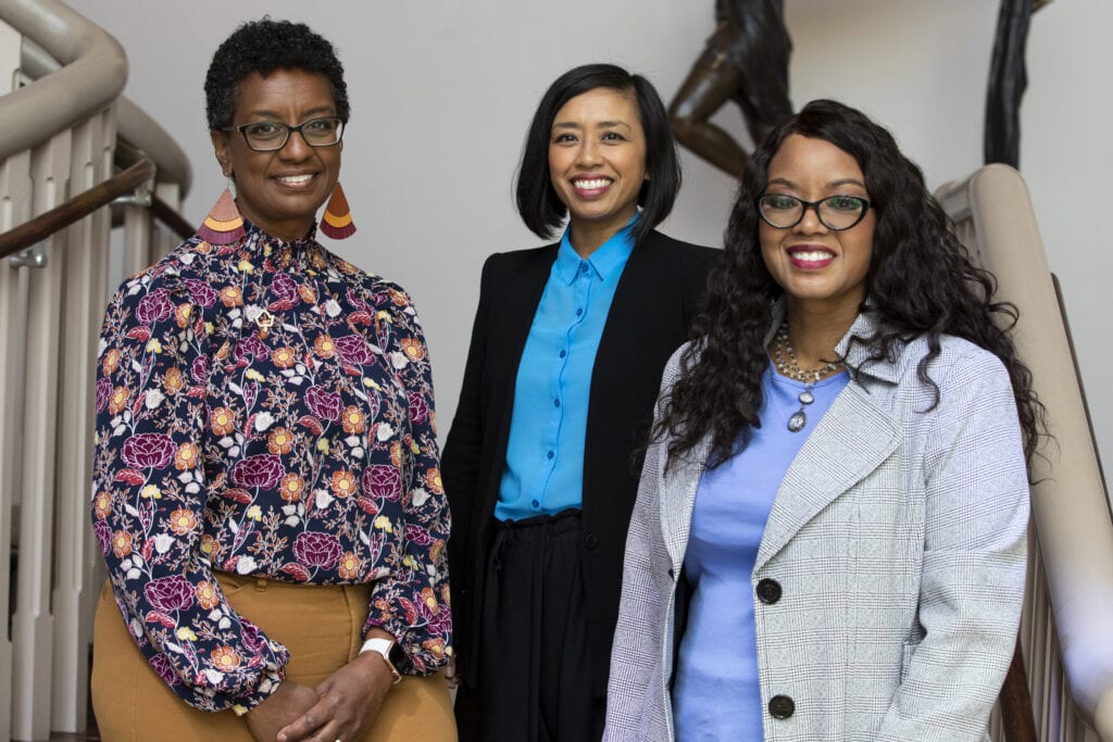 three women stand on stairs for Women's Leadership Colloquium