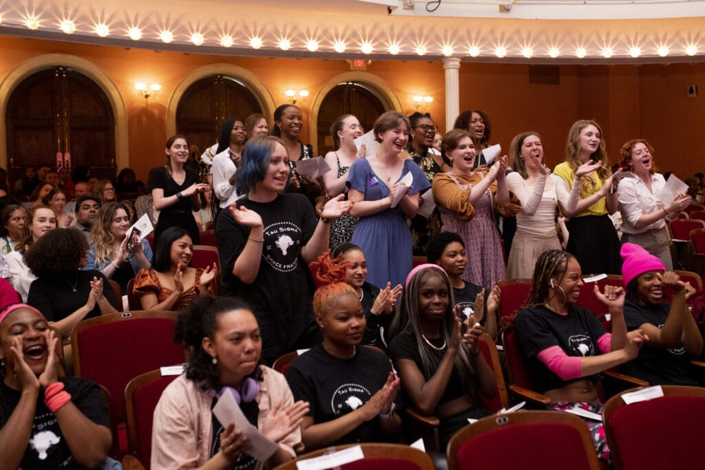 A group of female students give a standing ovation to a classmate in Pearce Auditorium.