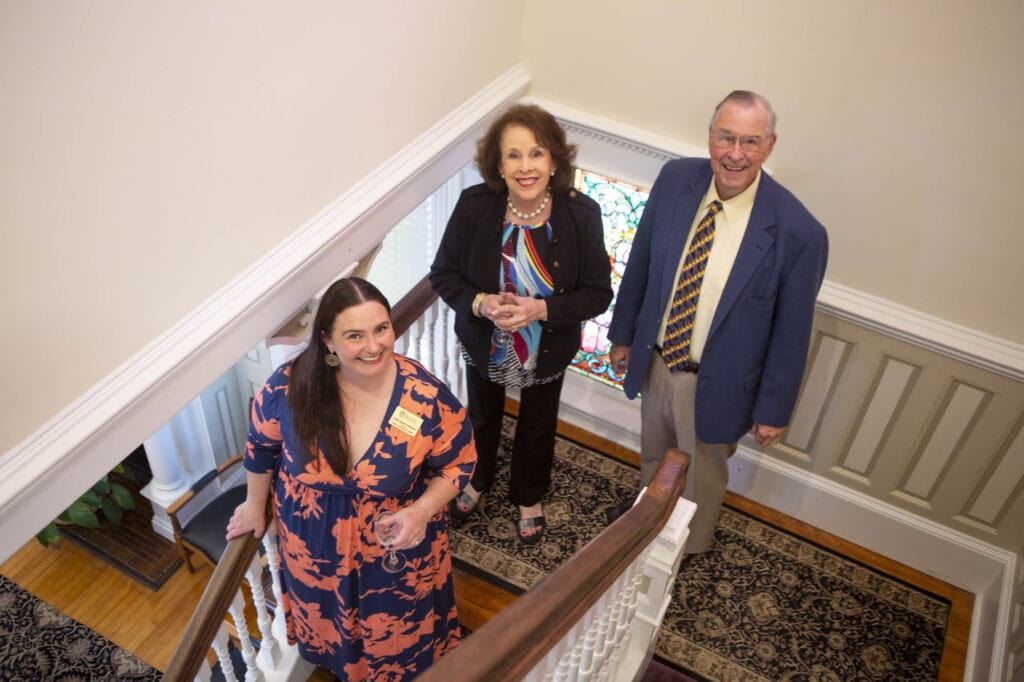 three people stand on a staircase landing, looking up