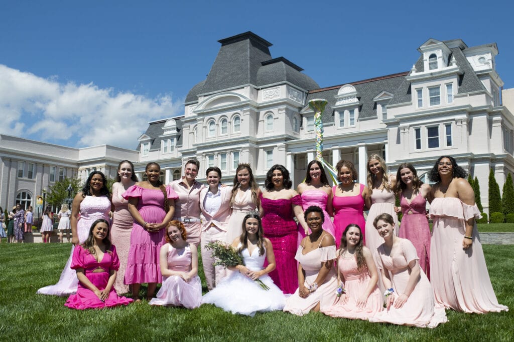 group of students wearing shades of pink and white on lawn in front of Pearce